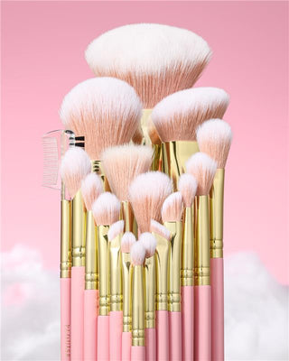 Set of makeup brushes with pink bristles and gold handles on a pink background