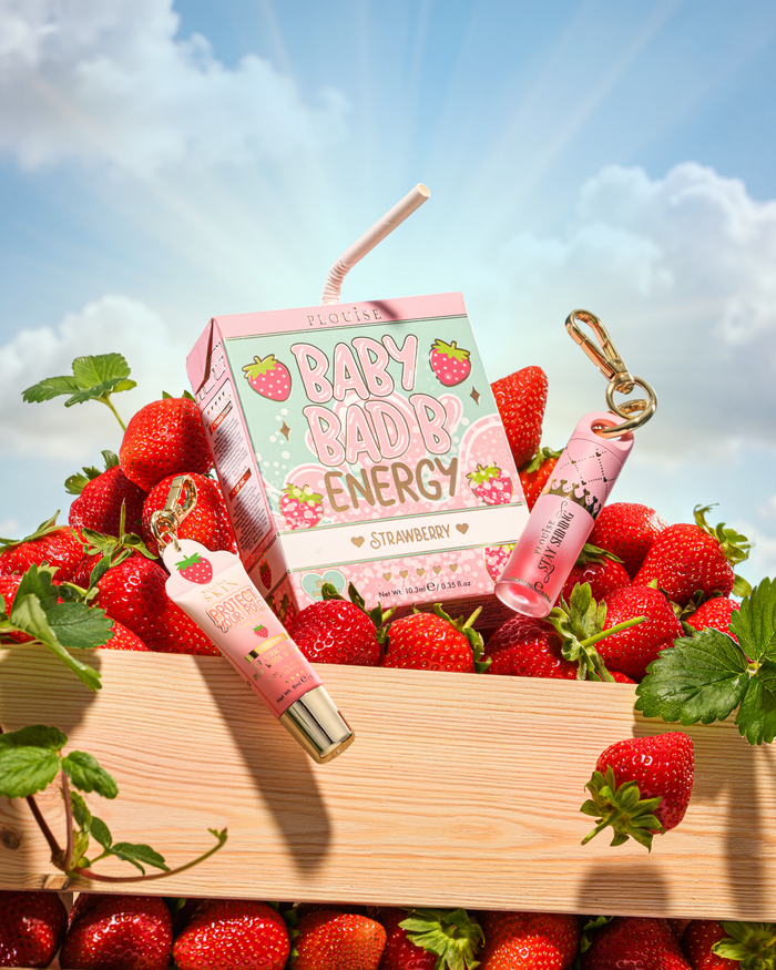 P.Louise Strawberry Baby Bad B 迷你唇油和迷你护唇膏放在草莓周围的桌子上