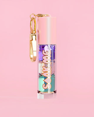 P. Louise Soak Me Lip Oil with colourful layered oil in a pink tube with a gold clasp on a pink background